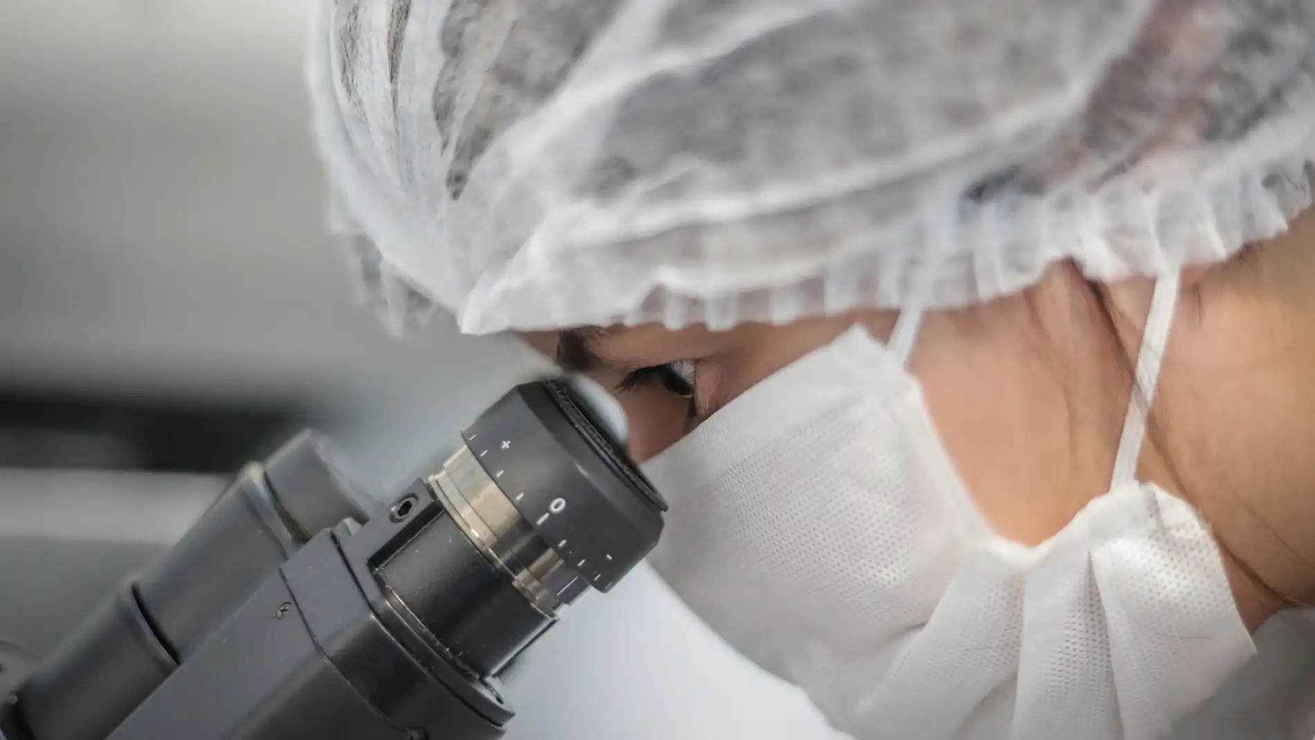 Científica mira a través de un microscopio en un laboratorio