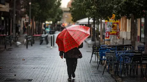 Una persona pasea con un paraguas bajo la lluvia.