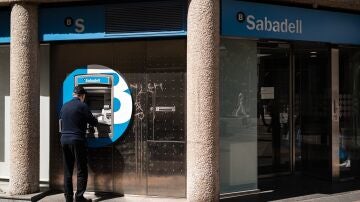 Un hombre en el cajero de la entidad bancaria de Sabadell que ha sido atracada, en la calle Núñez de Balboa