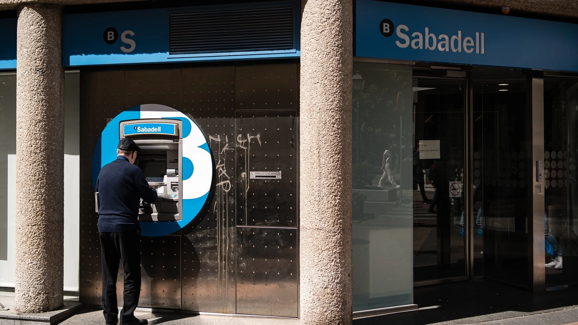 Un hombre en el cajero de la entidad bancaria de Sabadell que ha sido atracada, en la calle Núñez de Balboa