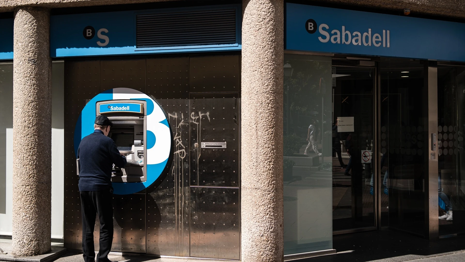 Un hombre en el cajero de la entidad bancaria de Sabadell que ha sido atracada, en la calle Núñez de Balboa