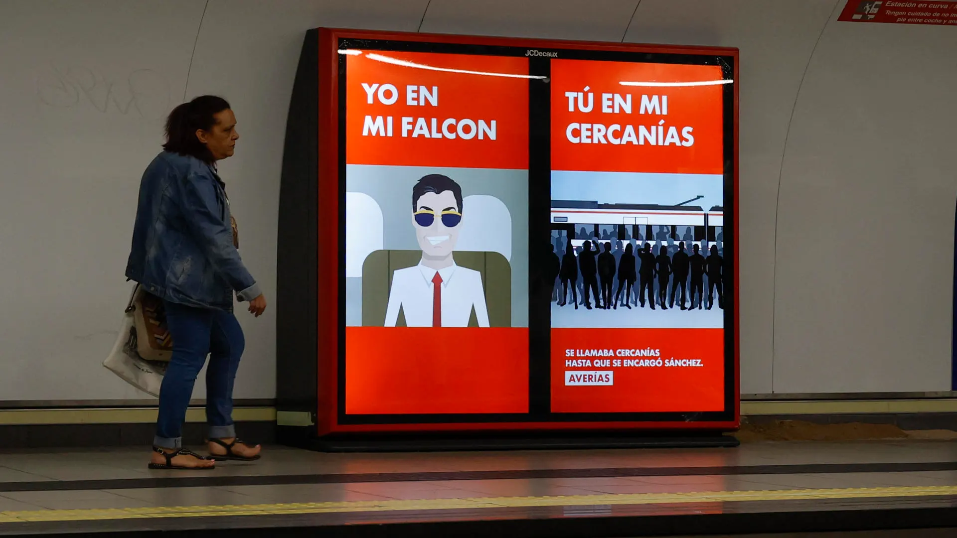 Una mujer pasa junto a unos luminosos con publicidad contra el presidente del Gobierno, Pedro Sánchez, este viernes en una estación del metro de Madrid