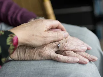 una mano anciana cogida por un sanitario una mano anciana cogida por un sanitario