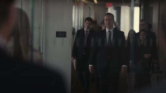 Varios personajes observan la llegada de Tom Wambsgans y un gran séquito, que nunca antes en 'Succession' ha recibido tanta atención.