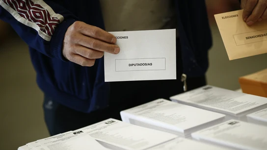 Una persona, votando en un proceso electoral con dos sobres en las manos Una persona, votando en un proceso electoral con dos sobres en las manos