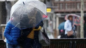 Imagen de archivo. Personas paseando bajo la lluvia con paraguas.