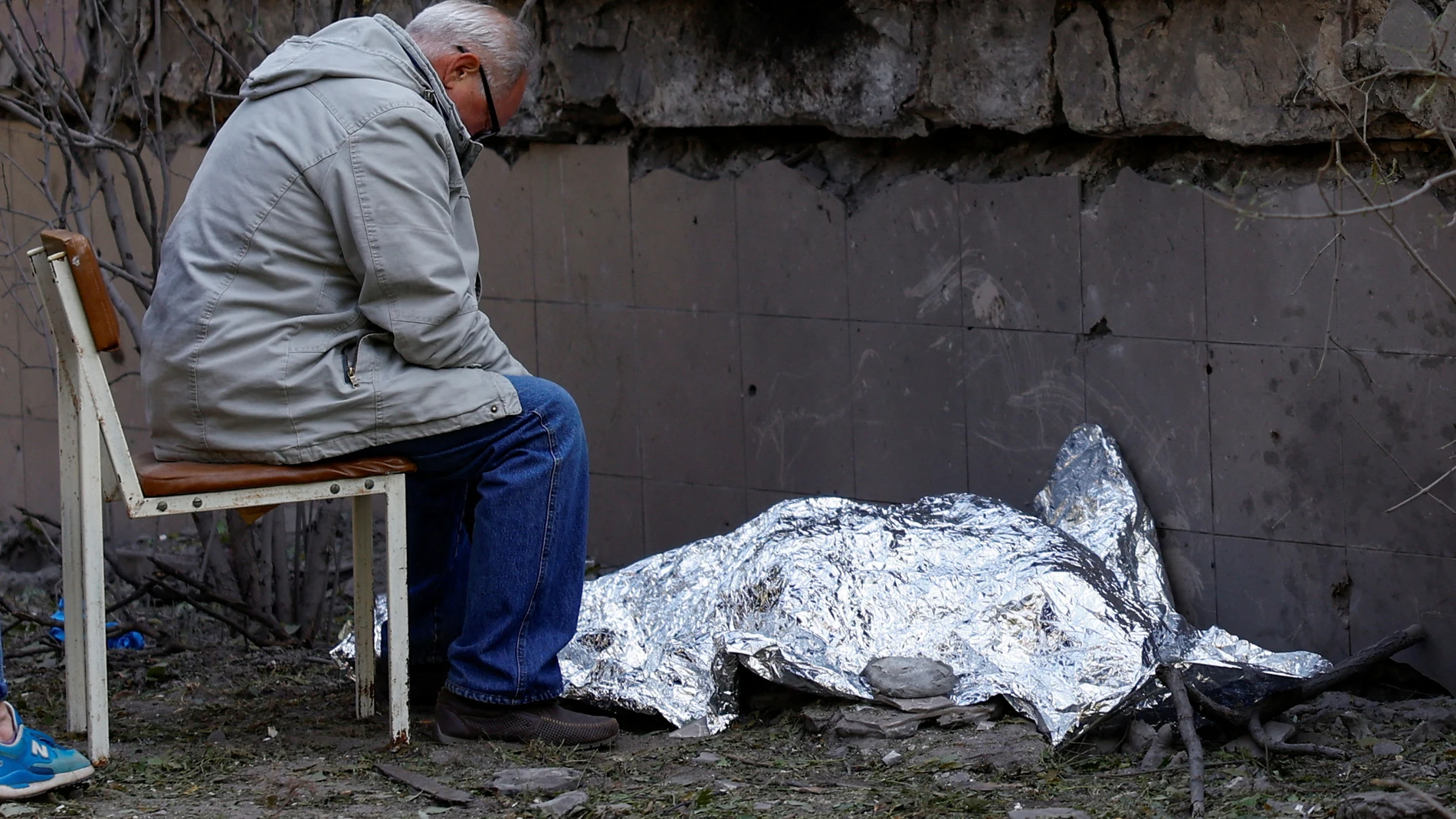 Un hombre se sienta junto al cuerpo de su nieta, que murió durante un ataque con misiles rusos en Kiev