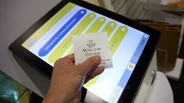 Una persona con un ticket de voto por correo en la oficina de Correos de Cibeles, en Madrid.