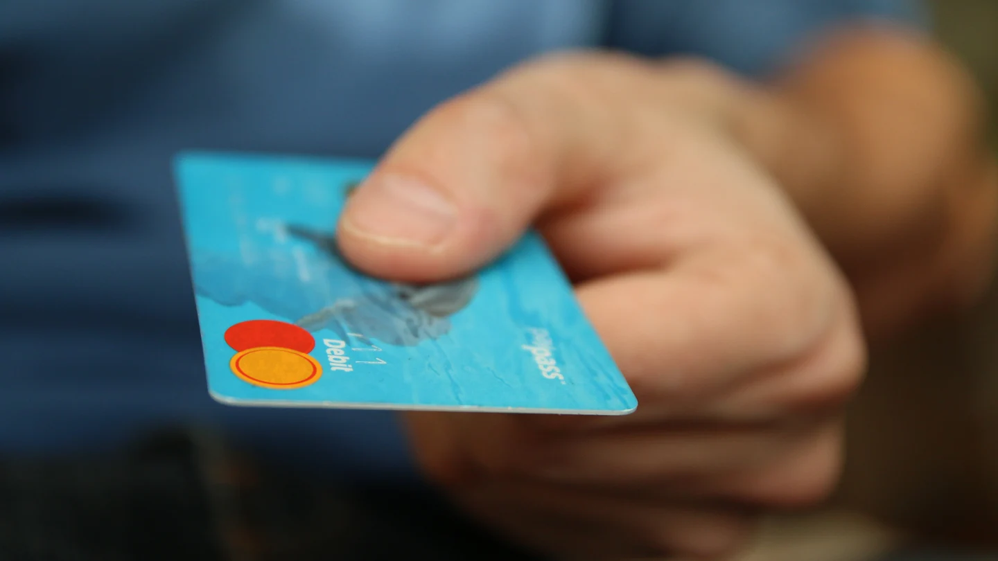 Una mano sosteniendo una tarjeta... ¿de crédito o de débito? Una mano sosteniendo una tarjeta... ¿de crédito o de débito?
