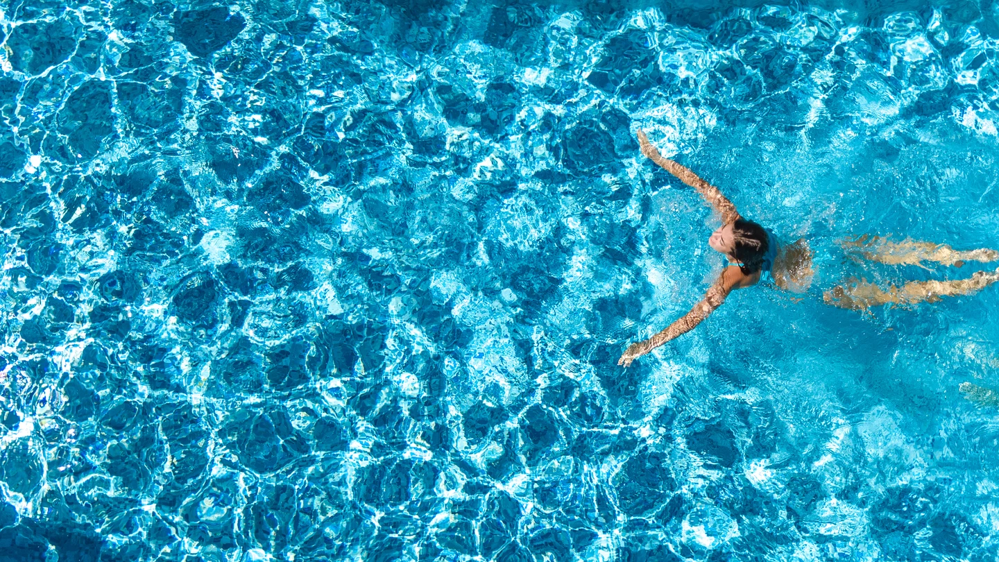 Chica joven nadando en una piscina Chica joven nadando en una piscina