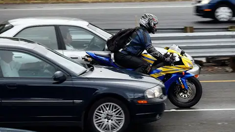 Motociclista entre coches, en autopista adelantando entre carriles.