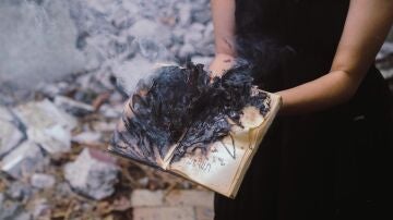 Mujer sosteniendo un libro quemado