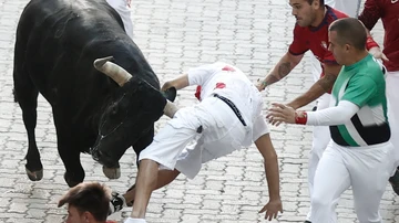 Un mozo es corneado por uno de los toros de la ganadería de Victoriano del Río durante del séptimo encierro de los sanfermines que ha durando dos minutos y 18 segundos de duración, este jueves en Pamplona. 