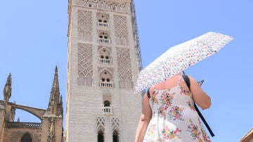 Una mujer pasea por los alrededores de la Catedral de Sevilla bajo su sombrilla para protegerse de las altas temperaturas