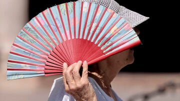 Una mujer se protege con un abanico del sol en Valencia.