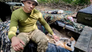 Sasha, un joven soldado voluntario ucraniano, acaricia a los gatos en una de las posiciones ucranianas junto a la frontera con Rusia, en Járkov este jueves. 