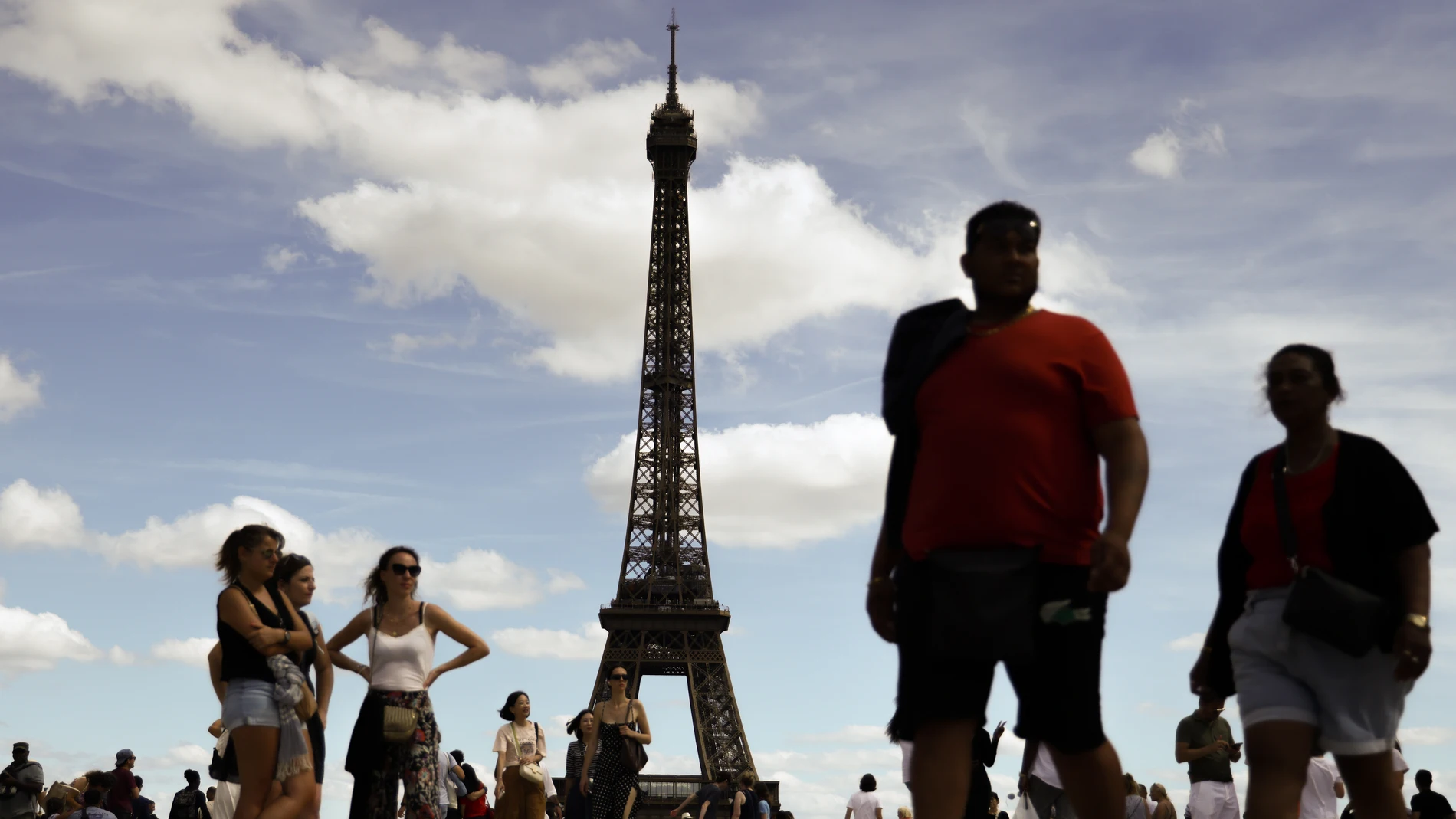 Decenas de personas pasean junto a la Torre Eiffel (París, Francia)