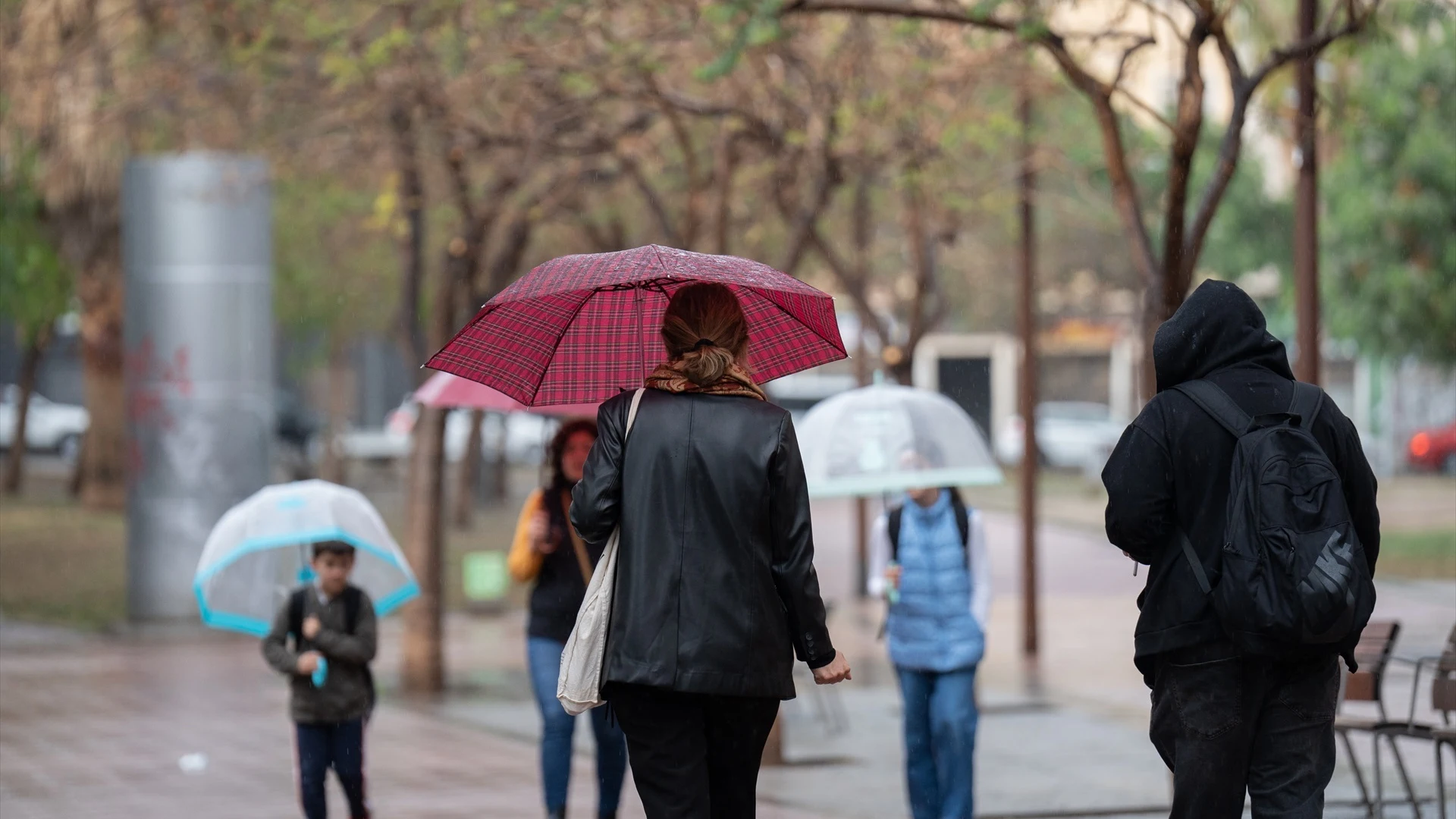 Imagen de archivo de varias personas caminando bajo la lluvia.