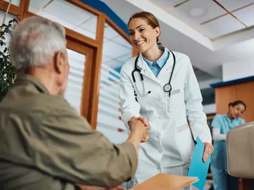 Un médico saluda a una persona mayor en la sala de espera Un médico saluda a una persona mayor en la sala de espera