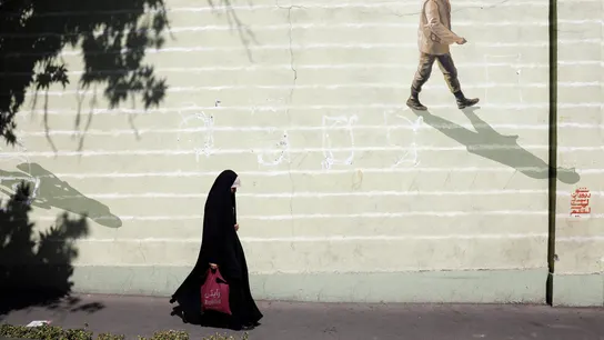 Imagen de archivo de una mujer iraní con velo que pasa junto a una pared con un soldado iraní pintado en ella en una calle de Teherán. Imagen de archivo de una mujer iraní con velo que pasa junto a una pared con un soldado iraní pintado en ella en una calle de Teherán.