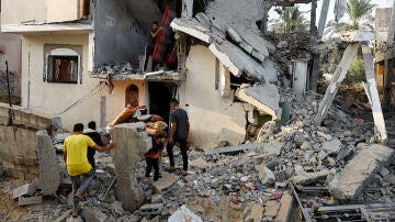 Los palestinos sacan pertenencias de una casa dañada en Khan Younis, en el sur de Gaza