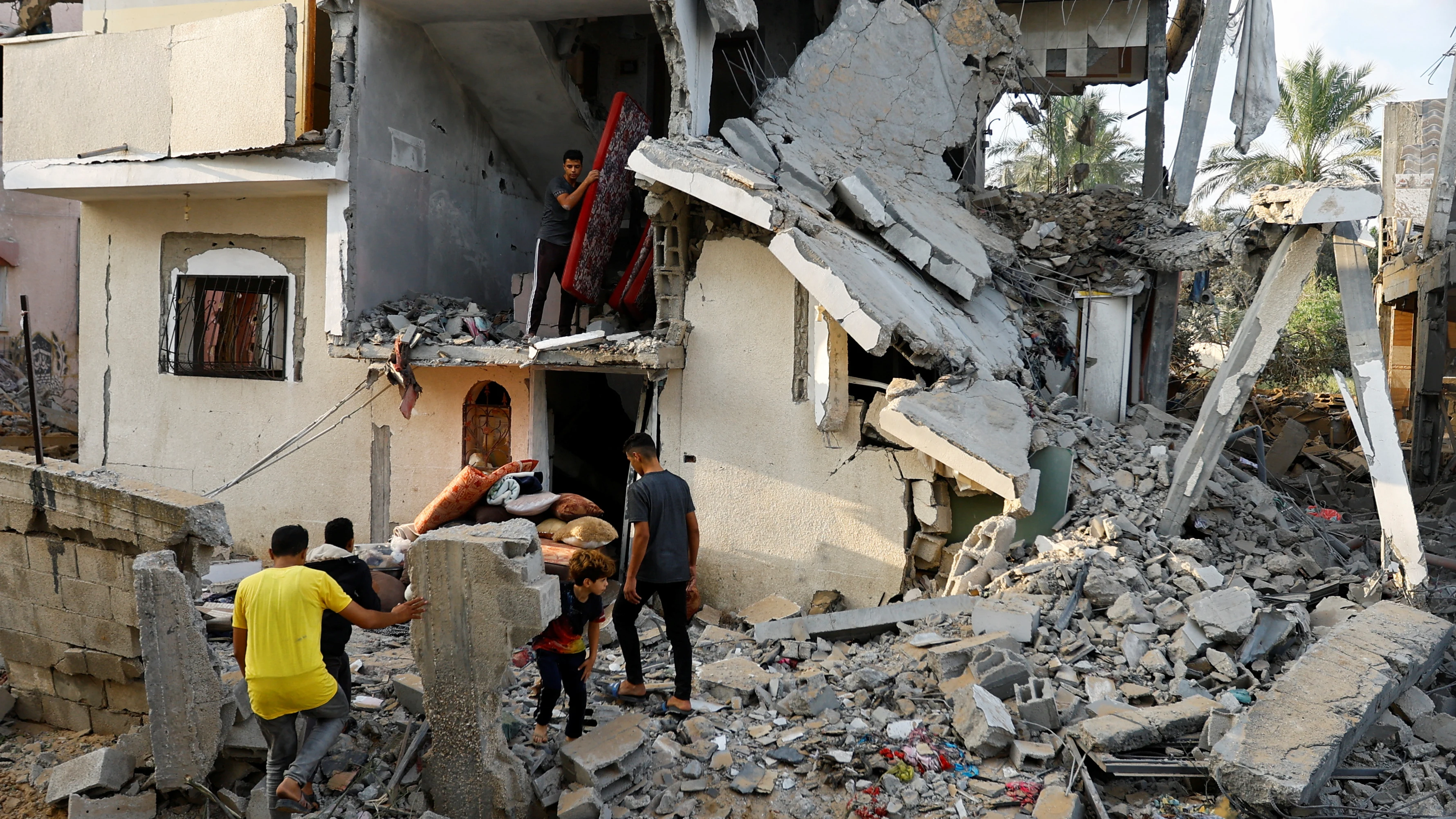 Los palestinos sacan pertenencias de una casa dañada en Khan Younis, en el sur de Gaza