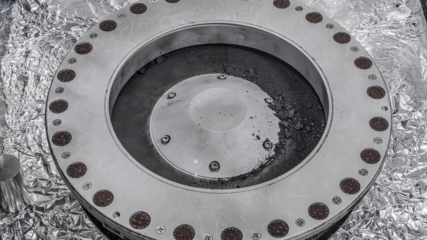 Fragmentos del asteroide Bennu traídos a la Tierra por la misión de la NASA OSIRIS-REx, vistos en la parte externa del recolector de muestras de la sonda Fragmentos del asteroide Bennu traídos a la Tierra por la misión de la NASA OSIRIS-REx, vistos en la parte externa del recolector de muestras de la sonda