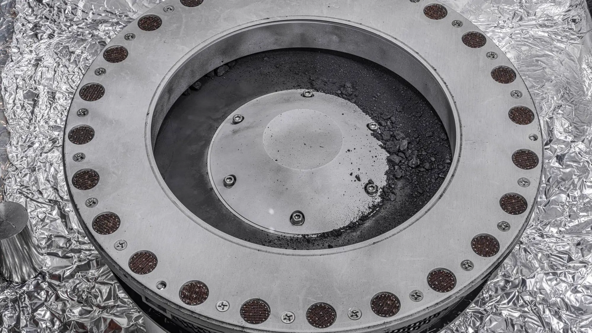Fragmentos del asteroide Bennu traídos a la Tierra por la misión de la NASA OSIRIS-REx, vistos en la parte externa del recolector de muestras de la sonda