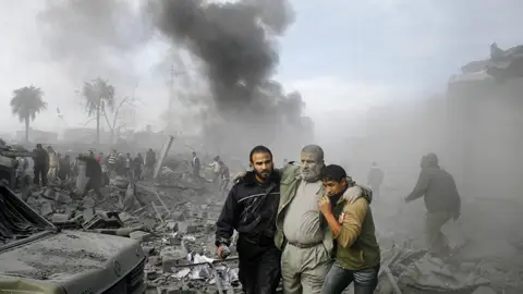 Un palestino herido recibe ayuda desde los escombros luego de un ataque con misiles israelí en el territorio gobernado por Hamás de Rafah, en el sur de la Franja de Gaza
