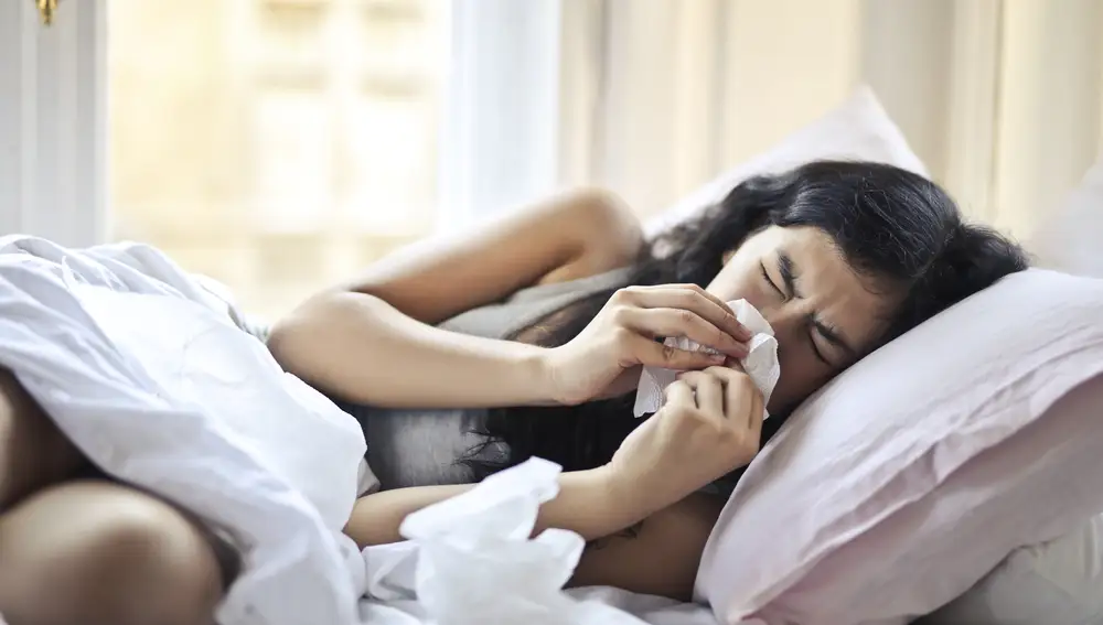Una mujer con un resfriado en la cama. 