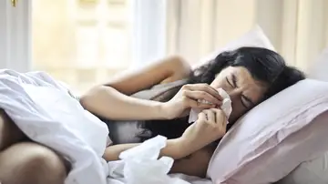 Una mujer con un resfriado en la cama. Una mujer con un resfriado en la cama.