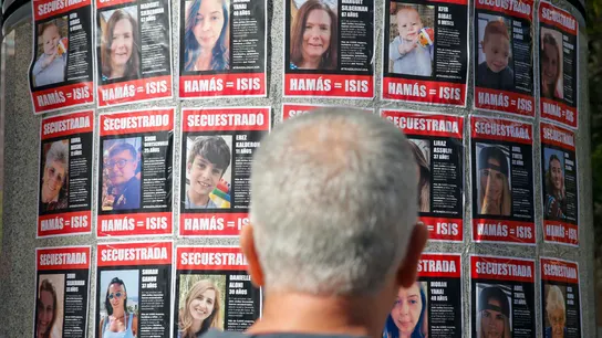 Una persona observa carteles con rostros de israelíes secuestrados en Gaza. Una persona observa carteles con rostros de israelíes secuestrados en Gaza.