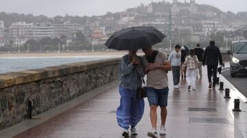 Imagen de archivo. Personas paseando bajo la lluvia.