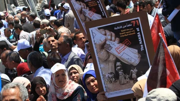 Manifestantes palestinos sostienen pancartas y banderas durante una concentración previa al 71º aniversario del &quot;Día de la Nakba&quot; (Día de la Catástrofe).