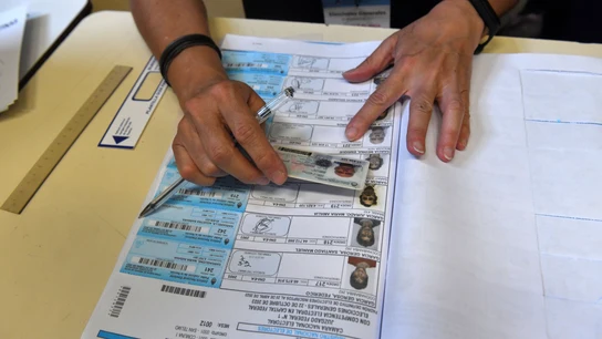 Un jurado de mesa confirmando la identidad de un votante en las elecciones presidenciales de Argentina Un jurado de mesa confirmando la identidad de un votante en las elecciones presidenciales de Argentina