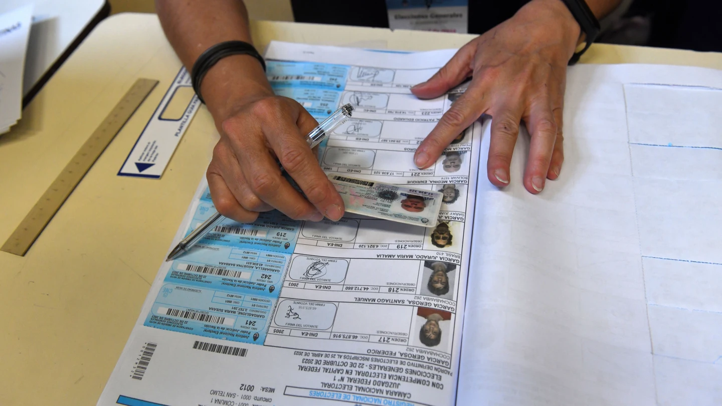Un jurado de mesa confirmando la identidad de un votante en las elecciones presidenciales de Argentina Un jurado de mesa confirmando la identidad de un votante en las elecciones presidenciales de Argentina