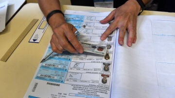 Un jurado de mesa confirmando la identidad de un votante en las elecciones presidenciales de Argentina