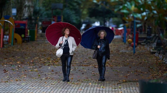 Imagen de archivo. Varias personas se cubren de la lluvia y el viento con paraguas. Imagen de archivo. Varias personas se cubren de la lluvia y el viento con paraguas.