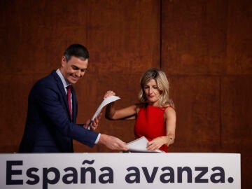 Pedro Sánchez y Yolanda Díaz intercambiándose los documentos del acuerdo firmado por ambos