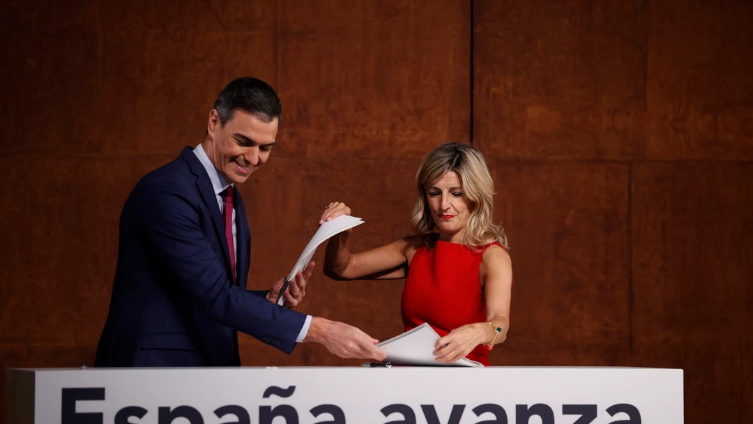 Pedro Sánchez y Yolanda Díaz intercambiándose los documentos del acuerdo firmado por ambos/ EFE/ Emilio Naranjo