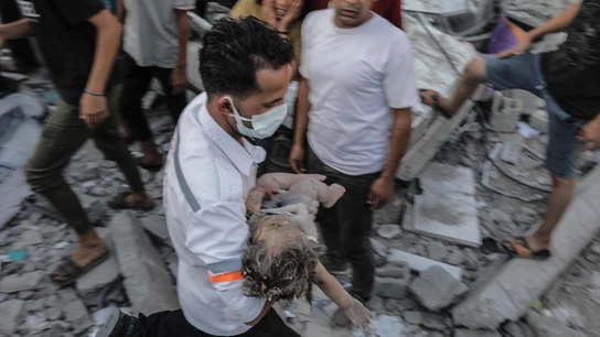 Un hombre rescata de entre los escombros a una niña tras un bombardeo israelí a edificios residenciales en Gaza Un hombre rescata de entre los escombros a una niña tras un bombardeo israelí a edificios residenciales en Gaza