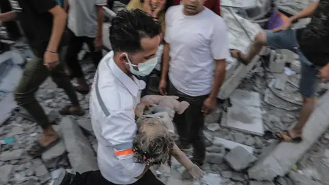 Un hombre rescata de entre los escombros a una niña tras un bombardeo israelí a edificios residenciales en Gaza