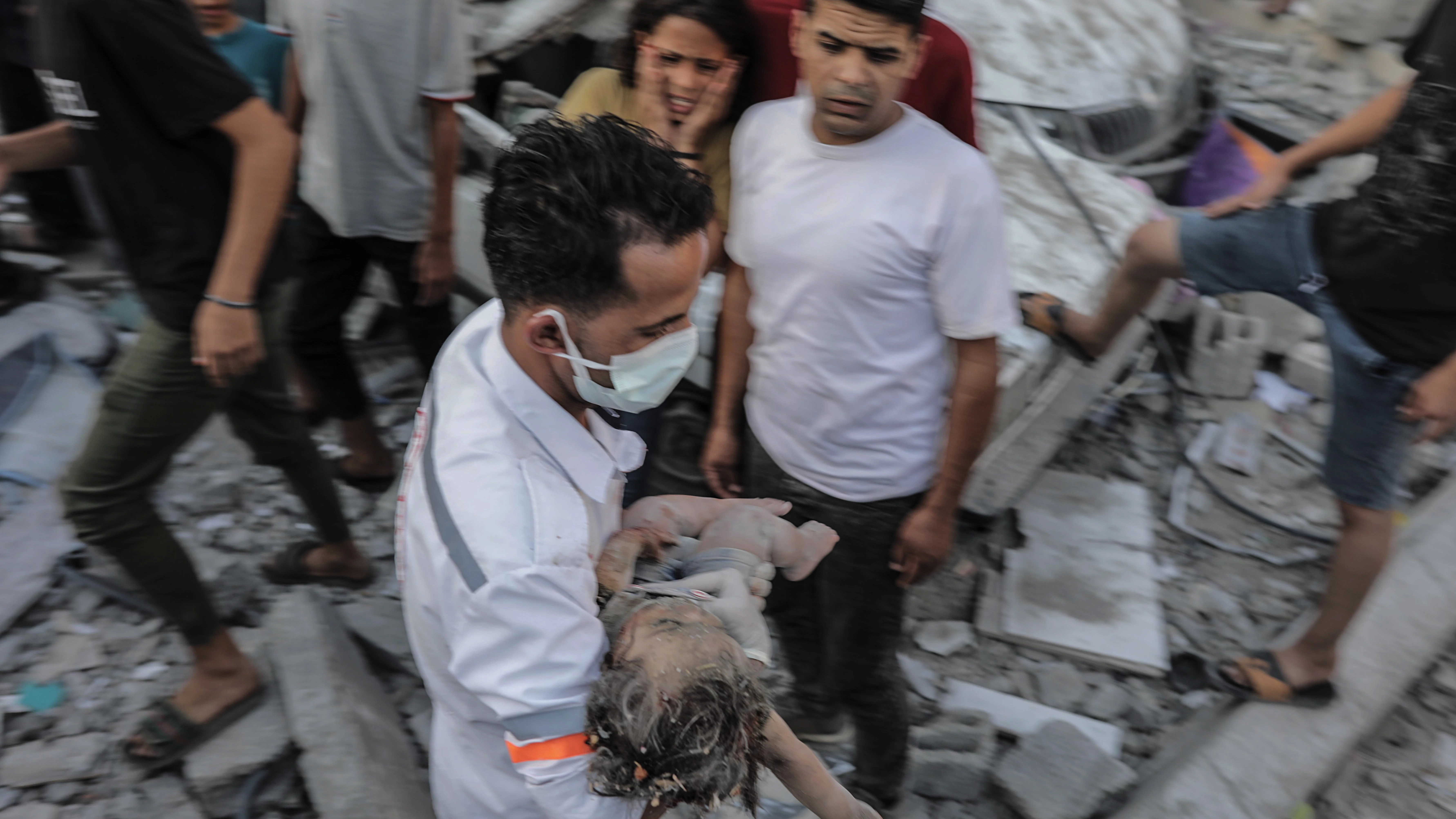 Un hombre rescata de entre los escombros a una niña tras un bombardeo israelí a edificios residenciales en Gaza