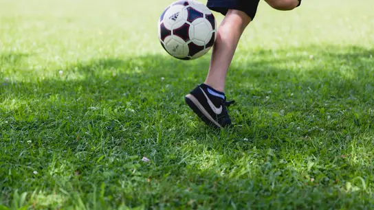 Imagen de archivo de un niño jugando al balón al aire libre Imagen de archivo de un niño jugando al balón al aire libre
