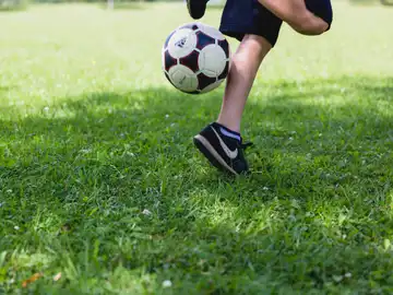 Imagen de archivo de un niño jugando al balón al aire libre