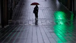 Una mujer camina con su paraguas bajo la lluvia en Galicia