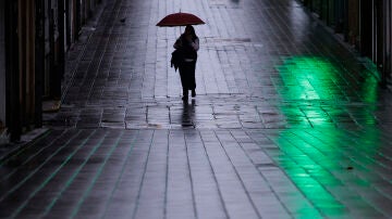 Una mujer camina con su paraguas bajo la lluvia en Galicia