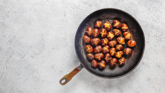 Una sartén llena de castañas recién asadas, un plato delicioso típico del otoño Una sartén llena de castañas recién asadas, un plato delicioso típico del otoño