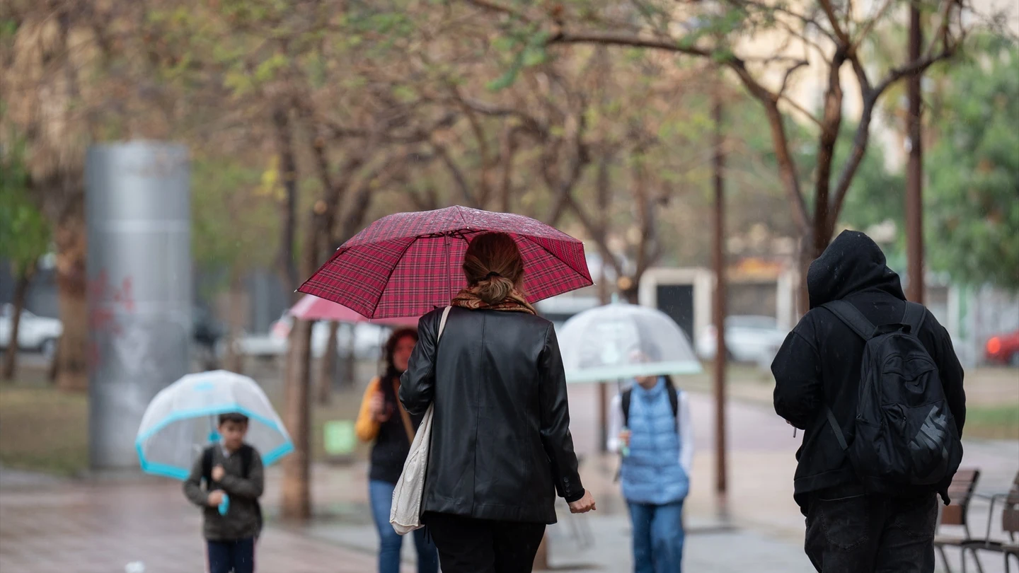 Varias personas con paraguas pasean por una de las calles de la ciudad. Varias personas con paraguas pasean por una de las calles de la ciudad.