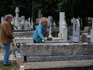 Una mujer deposita un ramo de flores en una lápida del cementerio de la Almudena, a 1 de noviembre de 2023, en Madrid (España).